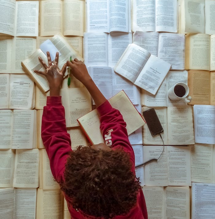 Aerial shot of a woman studying with books, coffee, and smartphone on a table.